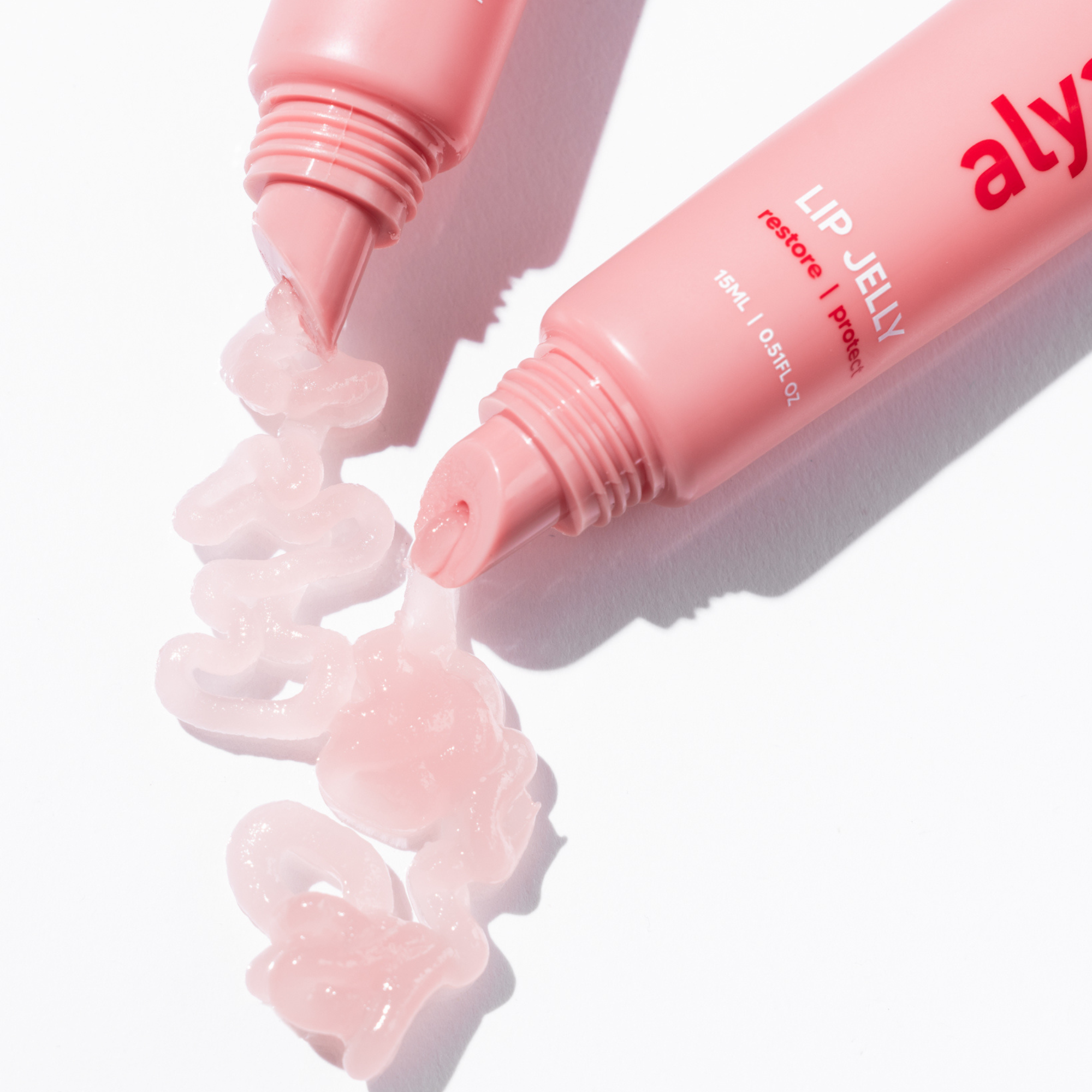 Alya Skin Pink lip jelly being squeezed from a tube on a white background