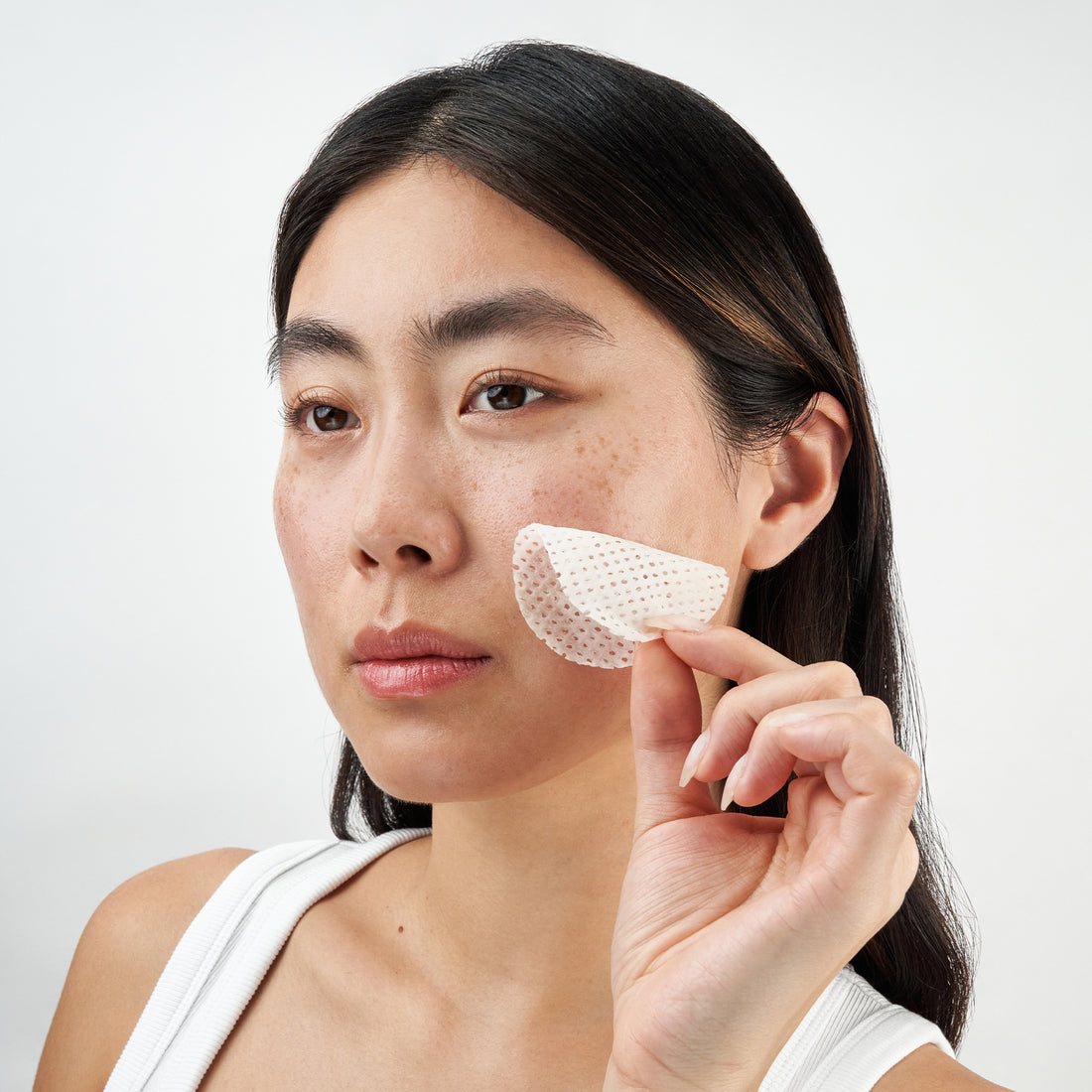Model gently applying toner pad to face, showcasing smooth, glowing skin and effortless skincare routine.