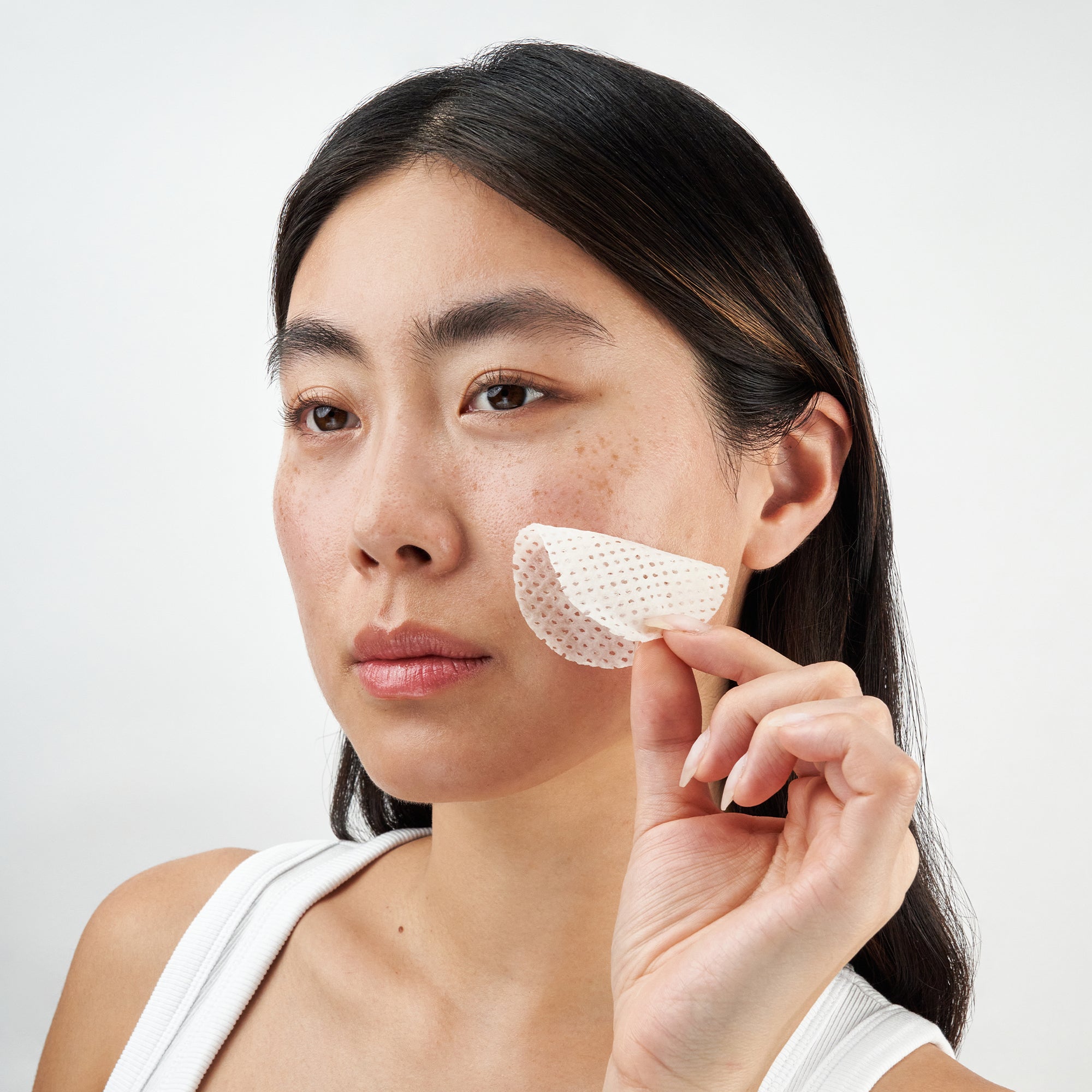 Model gently applying toner pad to face, showcasing smooth, glowing skin and effortless skincare routine.
