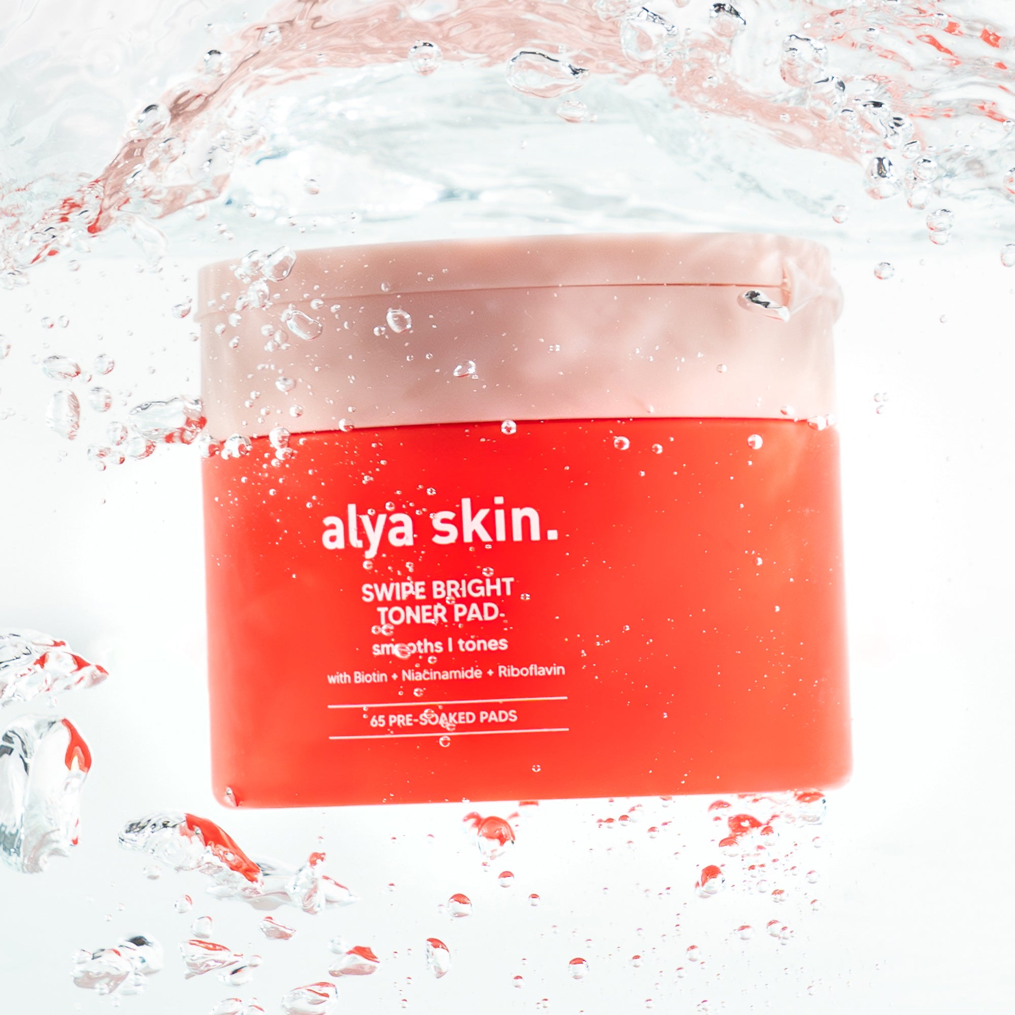 Red container of alya skin Swipe Bright Toner Pad with water droplets and splashes on a white background